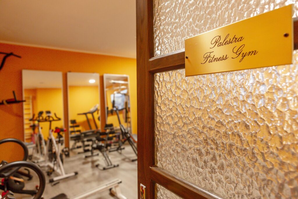 Porta a vetri con targa dorata Palestra Fitness Gym e, oltre, attrezzi e specchi della sala fitness