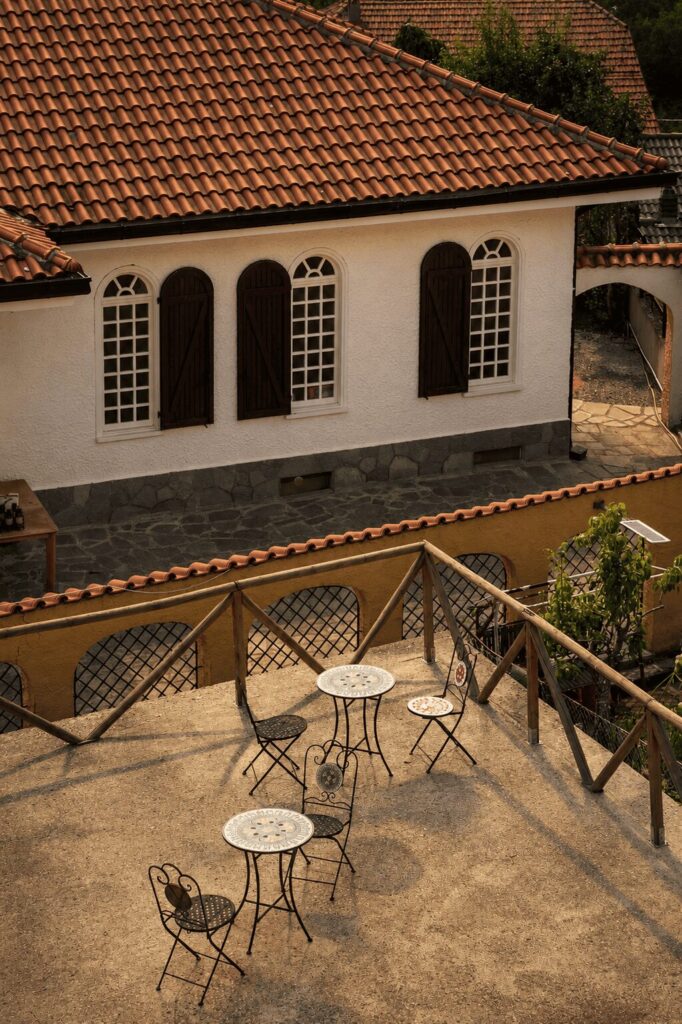 Vista dall'alto sul cortile con tavolini in ferro e sul tetto in coppi dell'edificio bianco con finestre ad arco